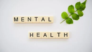 the word mental health spelled with scrabbles next to a green leaf